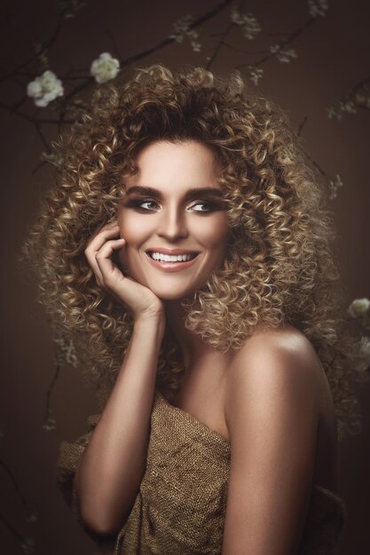 Portrait of lovely young woman with Afro hairstyle and beautiful make-up with a lot of white flowers on background