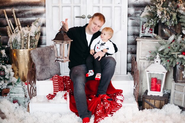 Portrait of loving dad with daughter on his shoulders decorating beautiful Christmas tree with toys and decoration at home