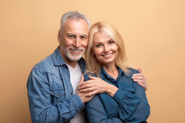 Portrait of loving happy senior couple spouses posing on beige