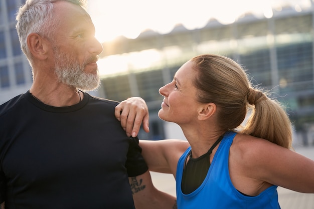 街で朝のトレーニングをしている愛する成熟したカップルのスポーティな男性と女性の肖像画