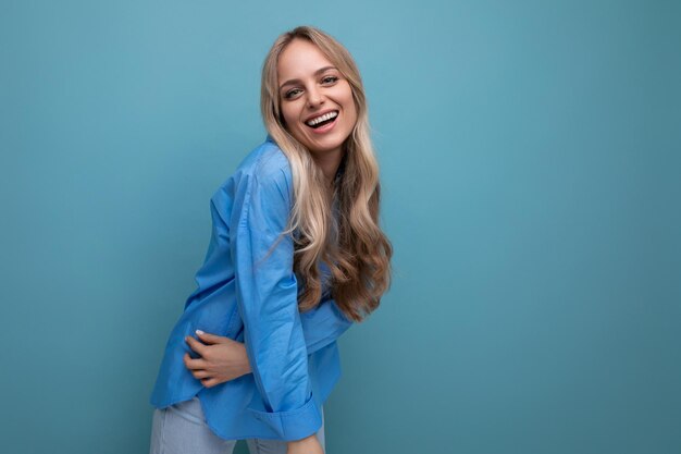 Portrait of a lucky adorable blonde young woman on a blue background with empty space