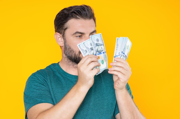 Portrait of lucky man holding cash dollar bills on yellow studio big luck banner dollar cash money