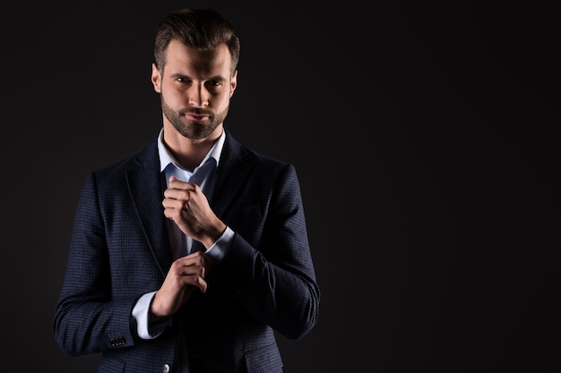 Portrait of luxurious well-dressed content guy model fastening
button