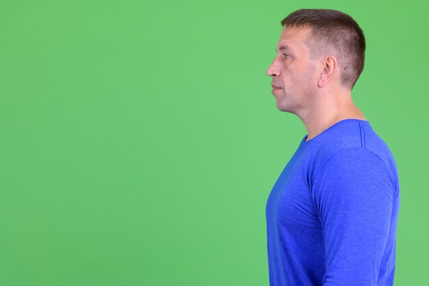 Photo portrait of macho mature man against chroma key with green wall