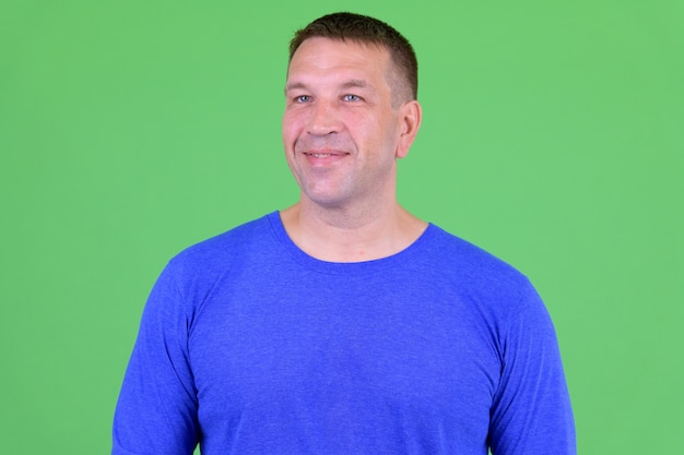 Portrait of macho mature man against chroma key with green wall