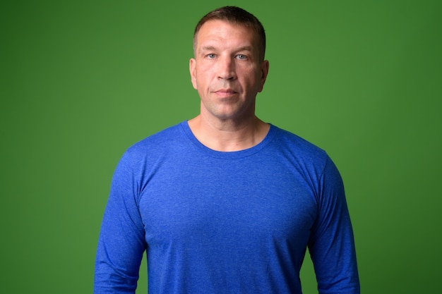 Portrait of macho mature man against chroma key with green wall