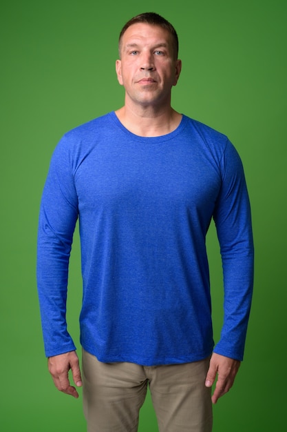 Photo portrait of macho mature man against chroma key with green wall