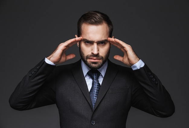 Portrait of a mad handsome businessman wearing suit isolated, having a headache