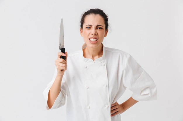 Photo portrait of a mad young woman with kitchen utensils
