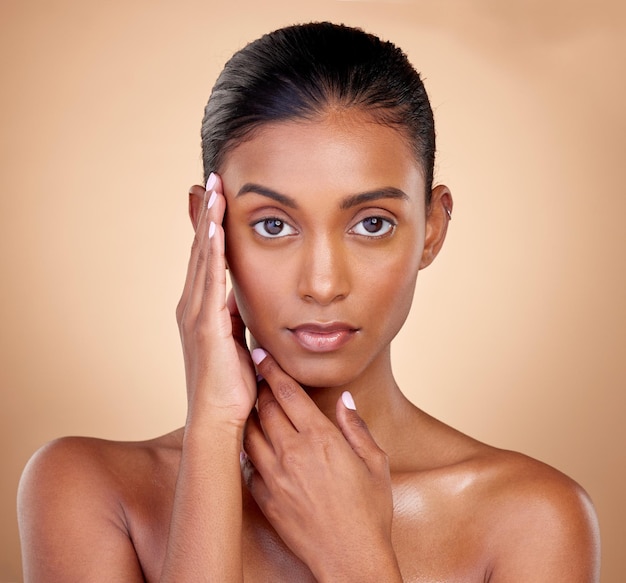 Portrait makeup and Indian woman with cosmetics dermatology and wellness against a brown studio background Face female person and model with health luxury and aesthetic with self care and beauty