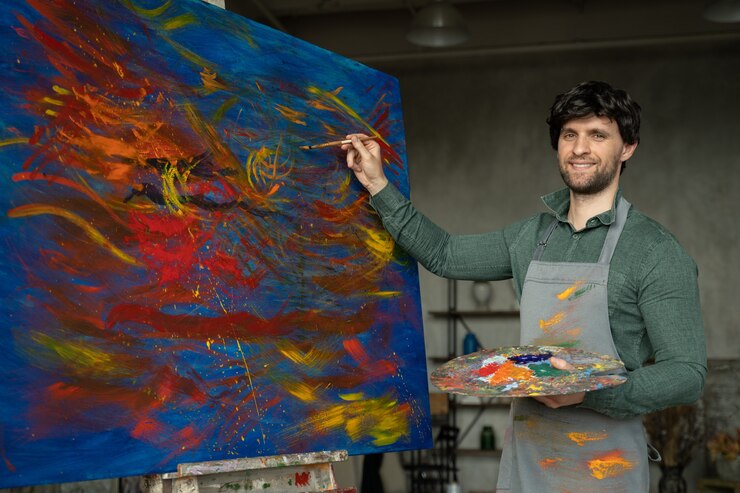 スタジオで絵画に取り組んでいる男性アーティストの肖像画男性アーティストは黄色のペンキでストロークを作成します
