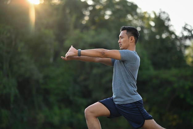 Portrait of male athlete stretching before morning workout in the park Active lifestyle concept