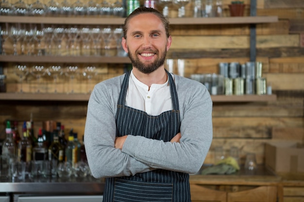 Portrait of male barista standing arms crossed in coffee shop