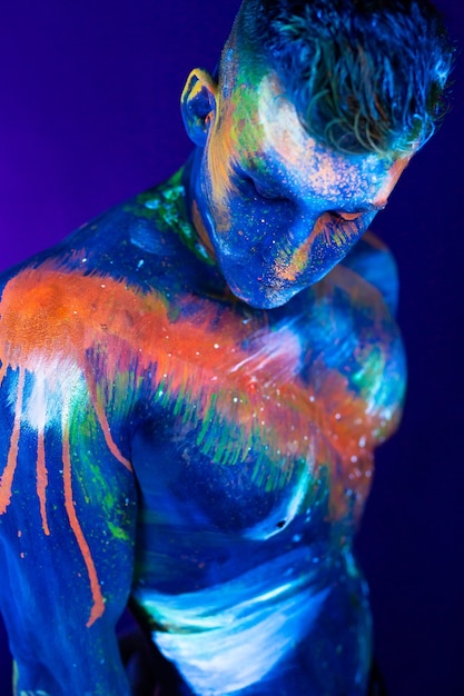 Portrait of a male bodybuilder. Man is painted in ultraviolet colors