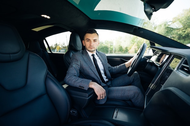 Portrait of male businessman sitting at the wheel of a car