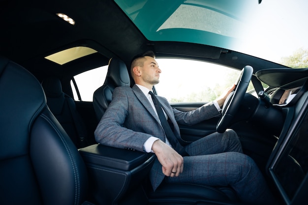 Portrait of male businessman sitting at the wheel of a car