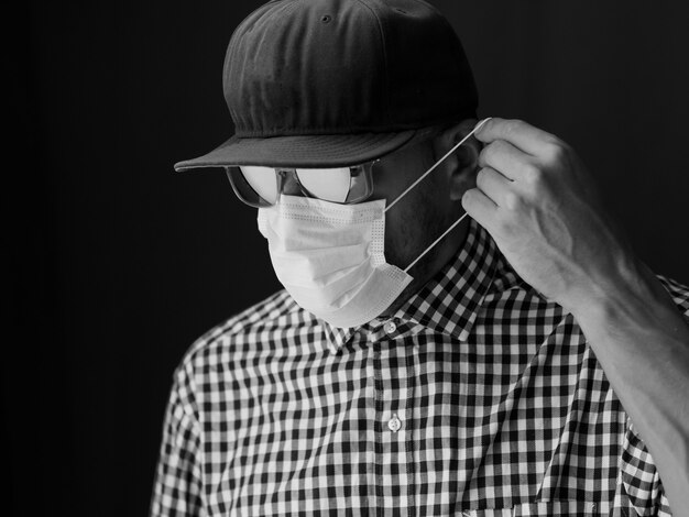 Portrait Male in a cap and sunglasses, put on medical face mask. black and white image.