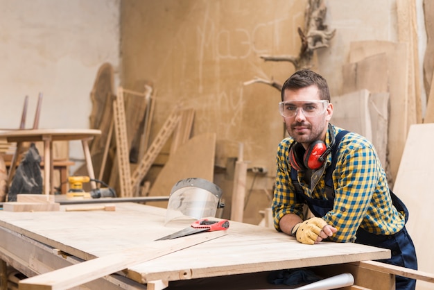 Портрет мужчины плотника, опираясь на верстак в мастерской