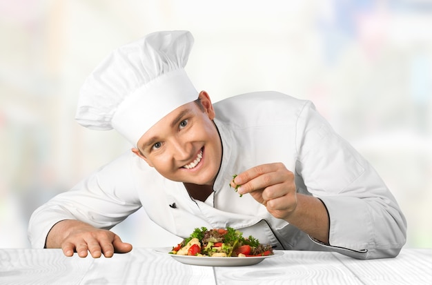 Portrait of a male chef cook preparing salad  isolated on  background