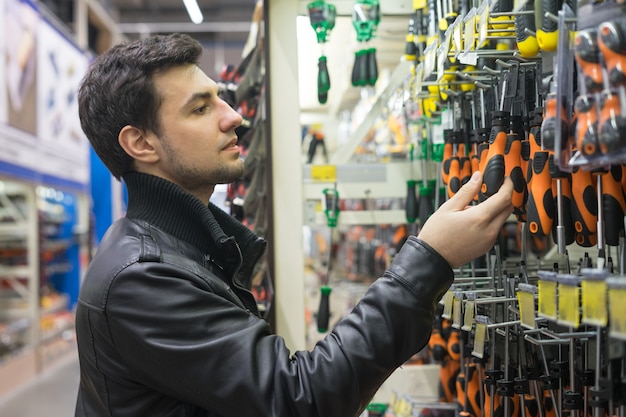 Portrait of male customer choosing screwdrivers or turn-screws at supermarket store