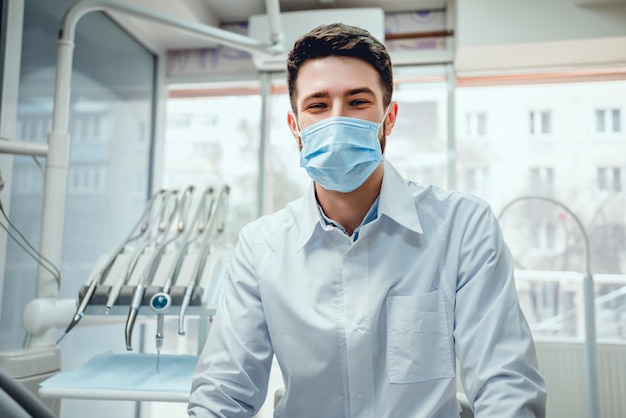 Foto ritratto di un dentista maschio in maschera nella sua clinica