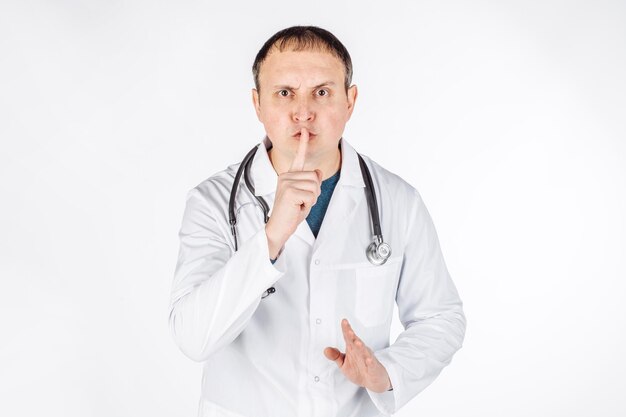 Portrait of a male doctor doing shush gesture as silence or secret