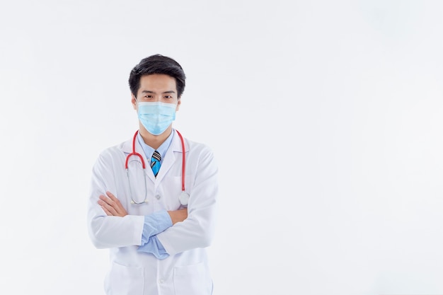 Portrait of a male doctor with arms crossed wearing a surgical mask.