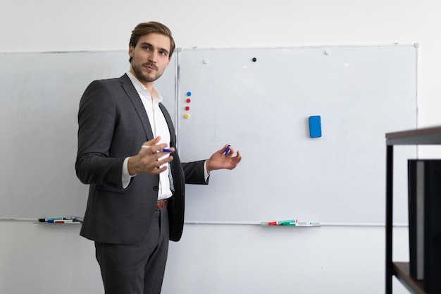 Portrait of a male financial worker explaining the situation of the firm in front of the blackboard