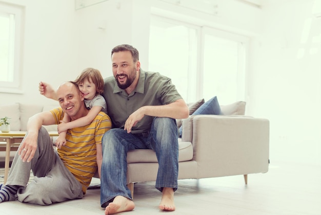 Portrait of male gay couple with adopted children little girl while having fun at home