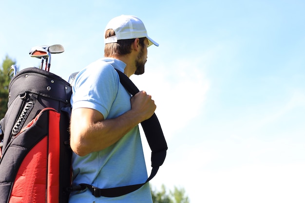골프 클럽의 푸른 잔디를 걷는 동안 골프 가방을 들고 남성 골퍼의 초상화.
