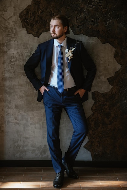 Portrait of a male groom in a blue suit in the morning barbershop