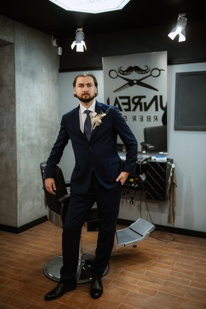 Portrait of a male groom in a blue suit in the morning barbershop