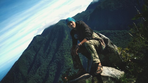 Photo portrait of male hiker sitting on rock against sky