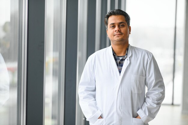 Portrait of male indian doctor on clinic corridor as background