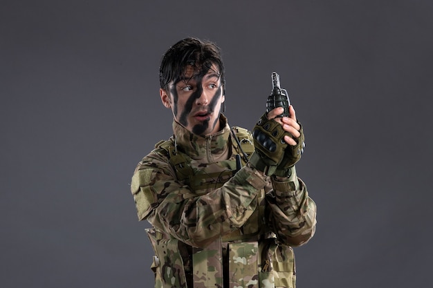 Portrait of male soldier during military operation with grenade on dark wall