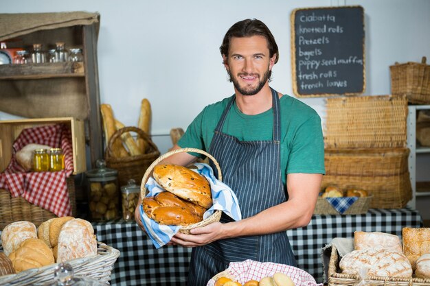 Portrait of male staff holding a basket of bread