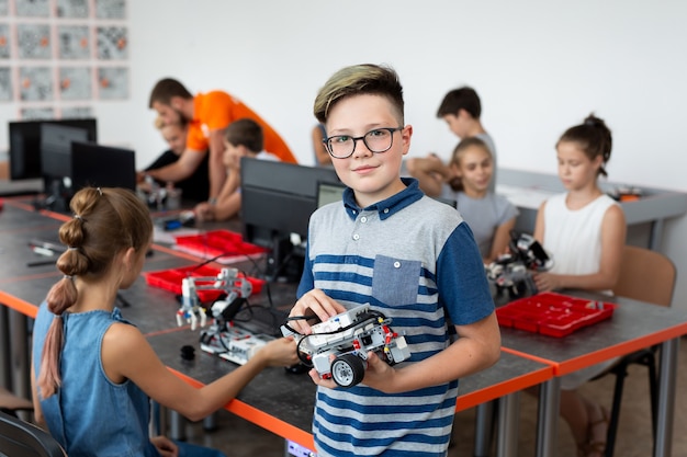 Portrait Of Male Student Building Robot Vehicle In After School Computer Coding Class