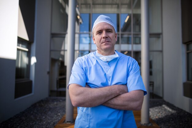 Portrait of male surgeon standing with arms crossed