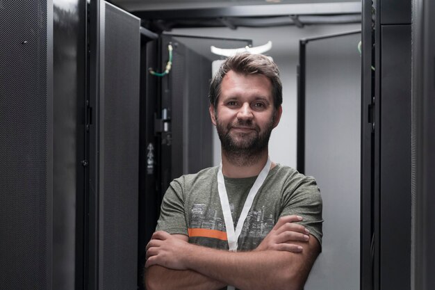 Portrait of male technician or network administrator standing\
brave as a hero with arms crossed in data center server room. high\
quality photo