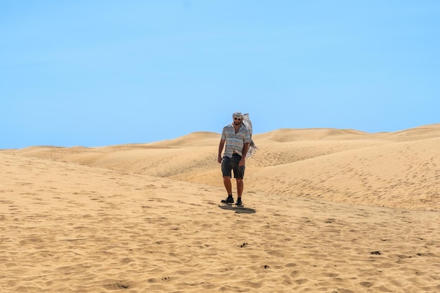 Portrait of male tourist in summer walking in the dunes of Maspalomas Gran Canaria Canary Islands