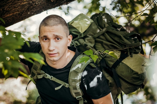 Портрет мужчины-туриста с рюкзаком, стоящего в лесу