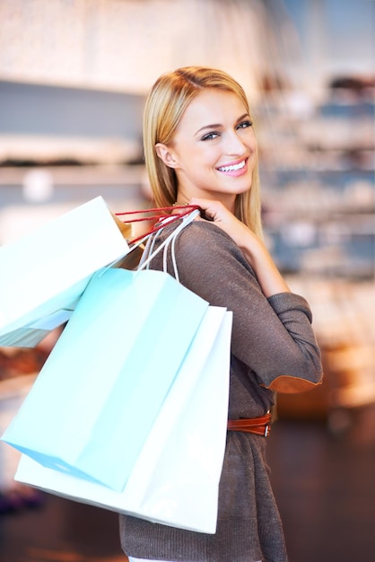 Portrait of a mall shopping woman customer and retail discount sale at a fashion boutique Beautiful female with a smile and shopping bags happy about store stock content spending money and cash