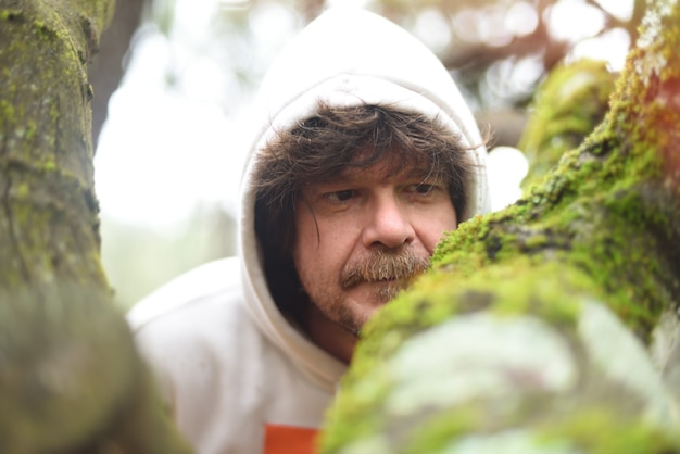 Portrait of man admiring ek moss on forest tree.