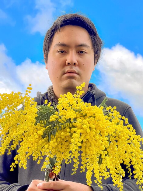 Portrait of man against yellow flowering plants against sky
