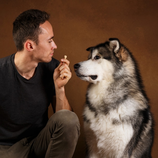 Foto ritratto di un uomo e di un cane alaskan malamute stitting