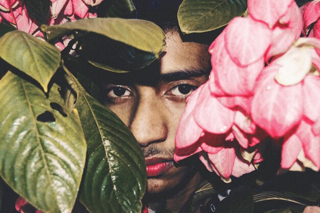 Photo portrait of man amidst pink flowers and green leaves