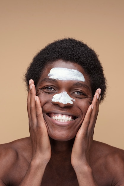 Photo portrait of a man applying moisturizer on his face