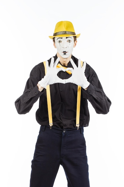 Photo portrait of a man artistclown mime shows a heart isolated on white background