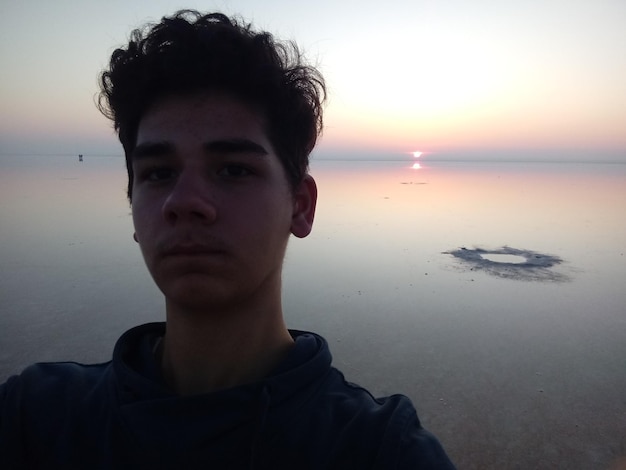 Foto ritratto di un uomo sulla spiaggia contro il cielo durante il tramonto