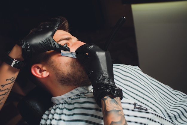 Portrait of man beard in barbershop. Female hand.